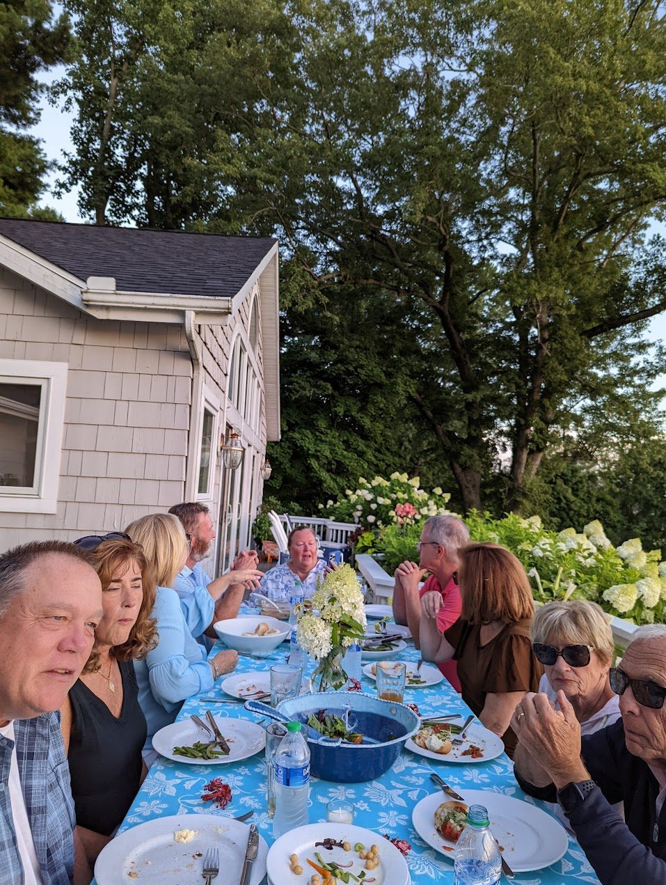 Friends gathered around the picnic table on the cottage deck, hydrangeas in bloom behind them